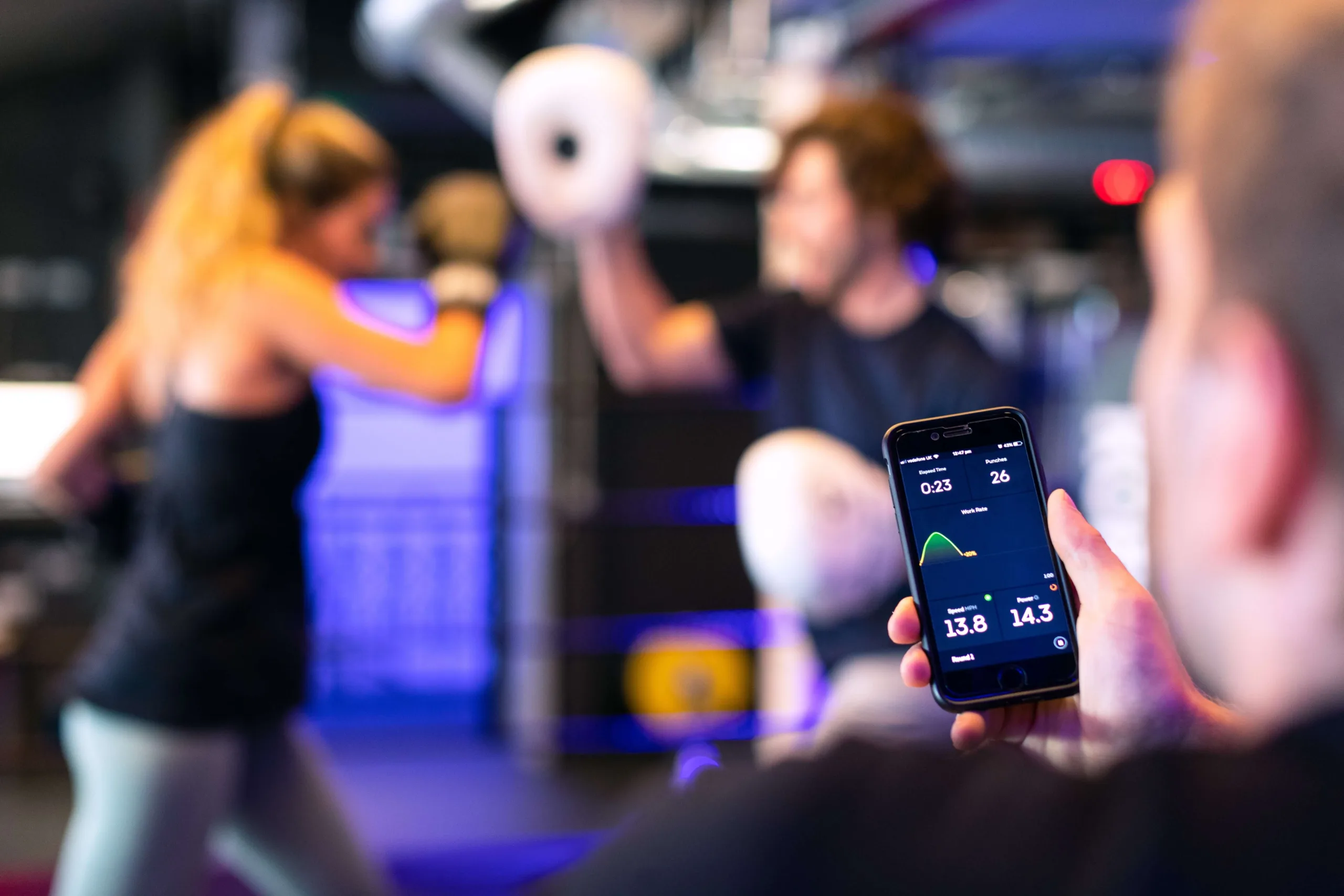 a personal trainer looking at his phone that is showing boxing data of his client