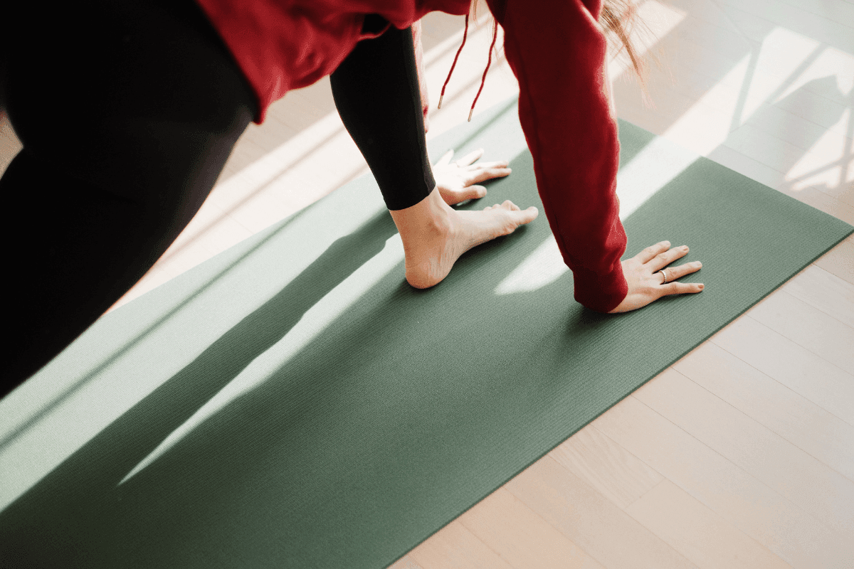 a person standing on a yoga mat a woman practicing yoga from the side as she gets up into warrior one